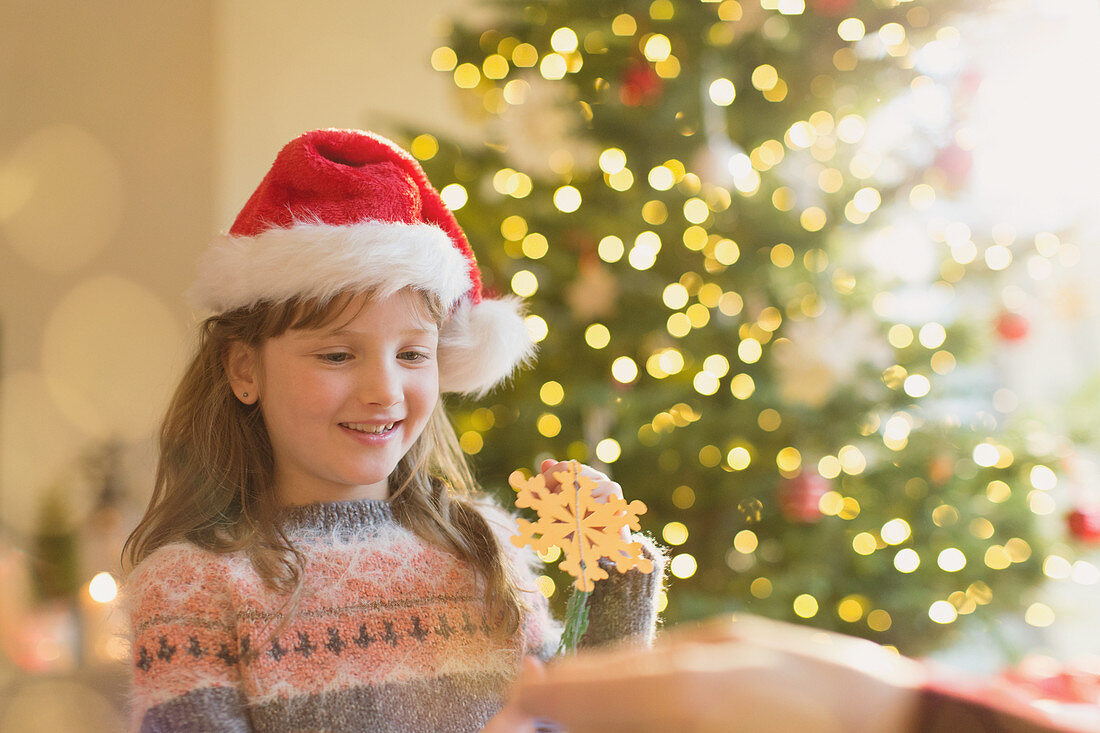 Girl in Santa hat holding snowflake ornament