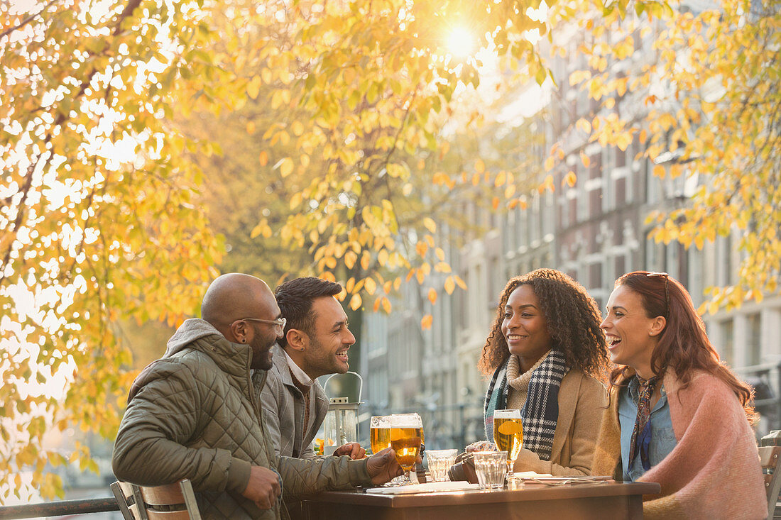 Friends drinking beer at outdoor autumn cafe