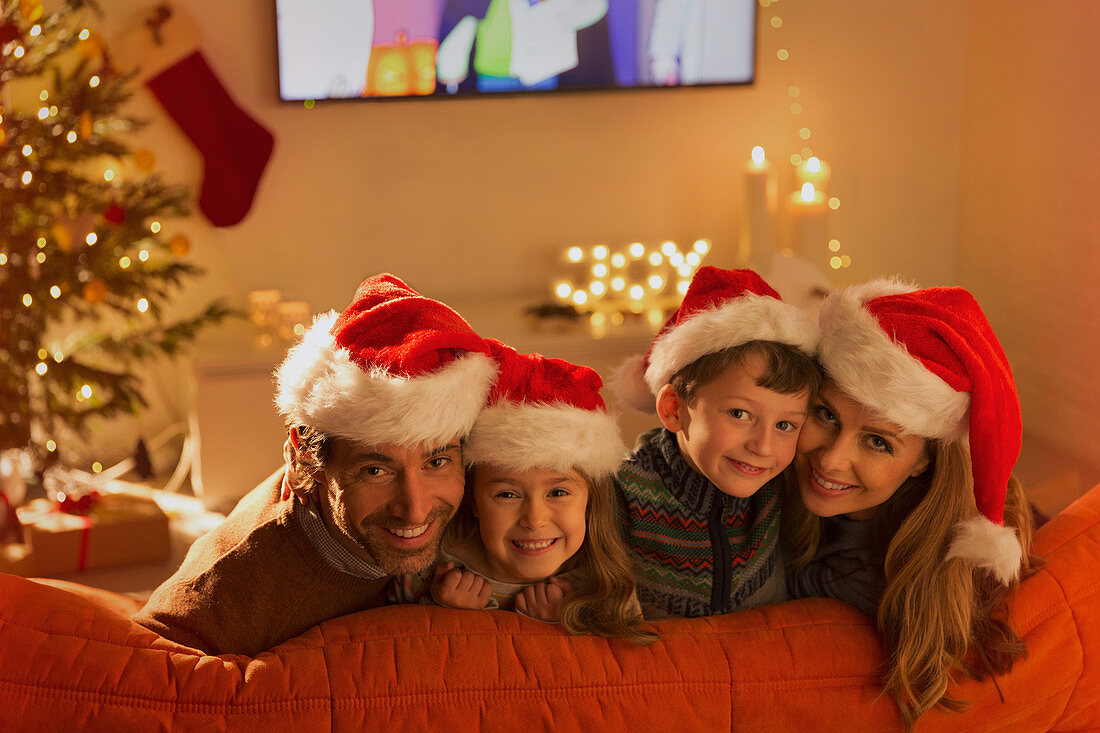 Smiling family wearing Santa hats on sofa