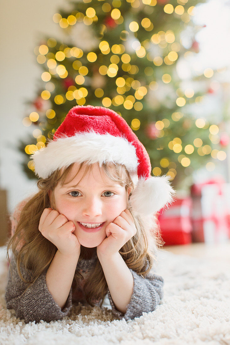 Smiling girl wearing Santa hat on rug