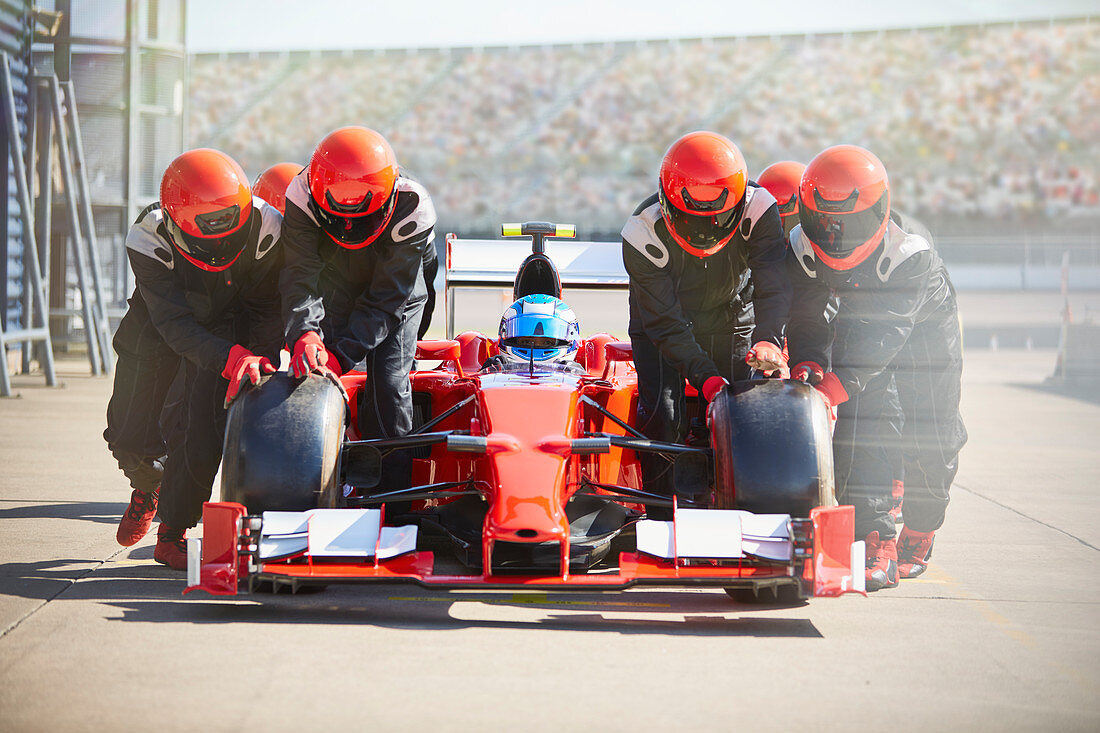 Pit crew pushing formula one race car