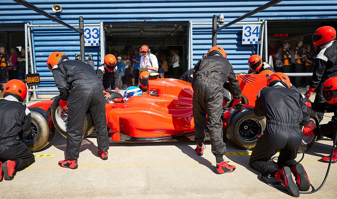 Pit crew replacing tires on formula one race car