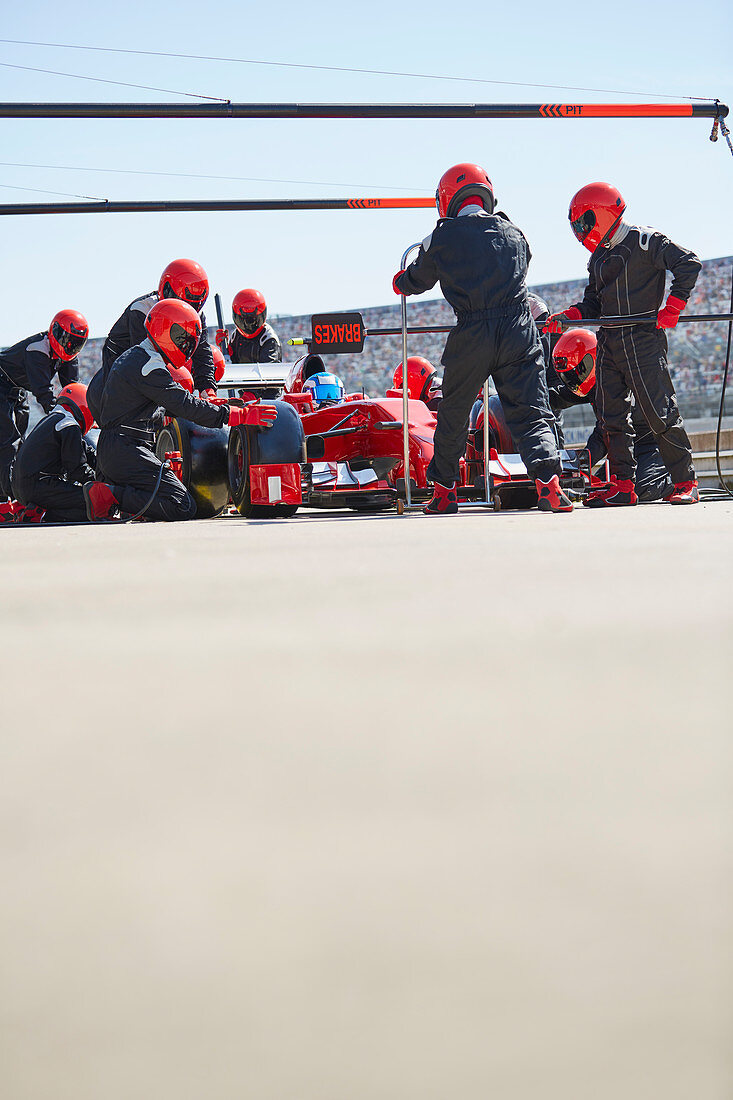 Pit crew replacing tires on formula one race car