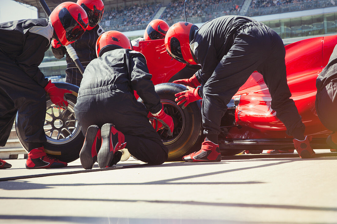 Pit crew replacing tires on formula one race car