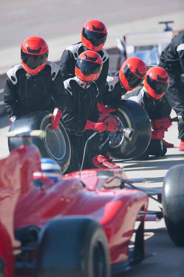 Pit crew with tires ready for nearing race car