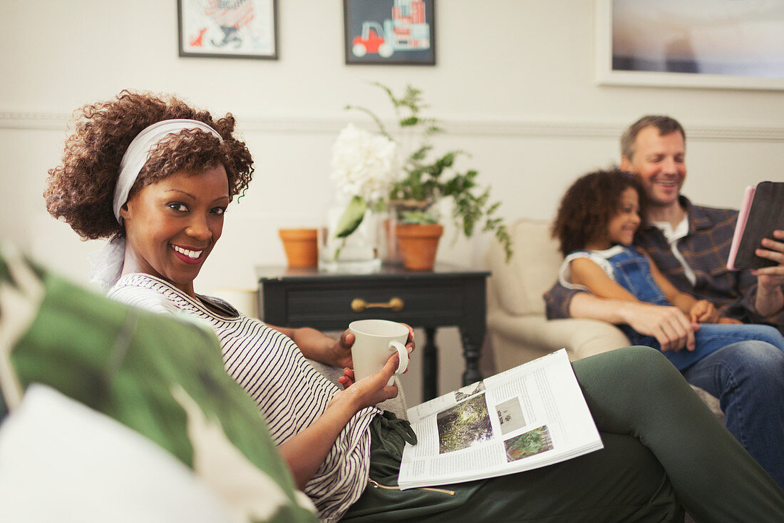 Woman relaxing with tea and magazine on sofa