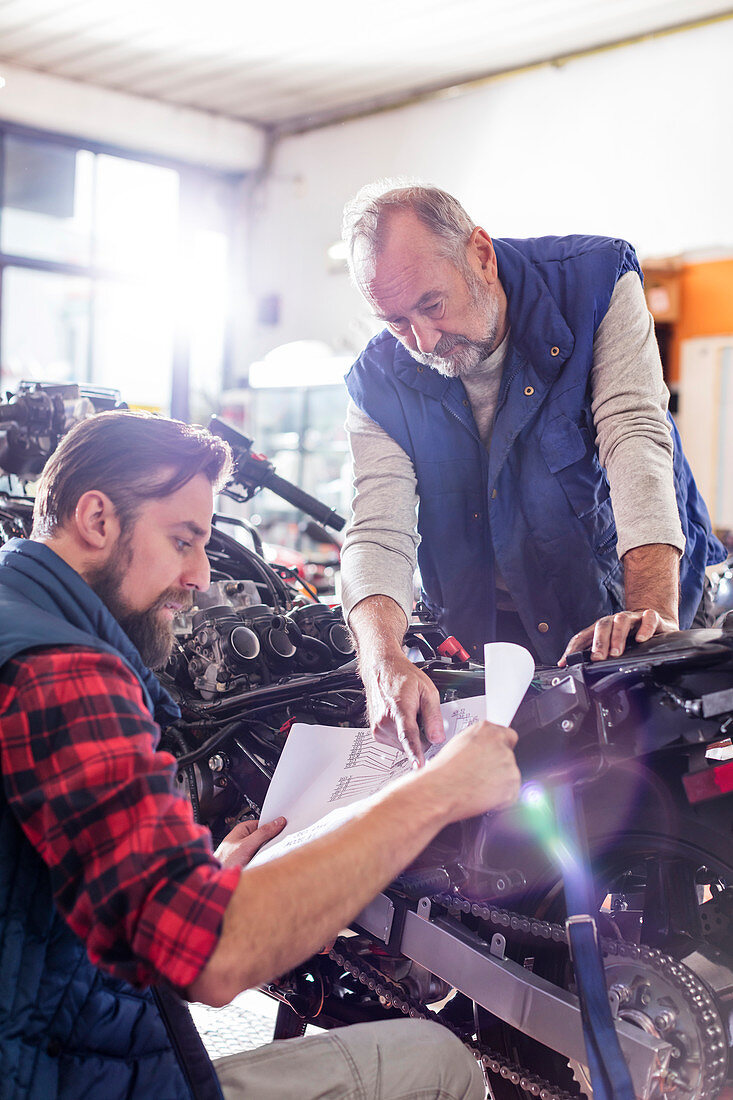 Male motorcycle mechanics reviewing plans