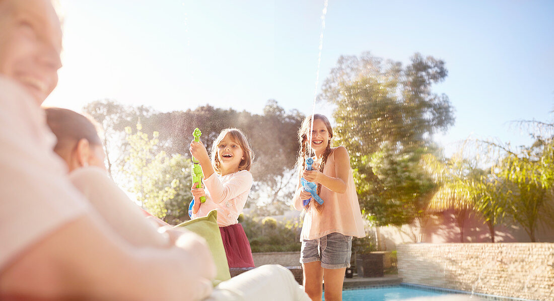 Playful sisters with squirt guns spraying water