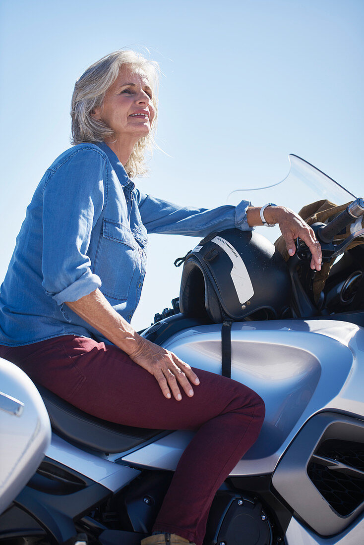 Smiling senior woman sitting on motorcycle