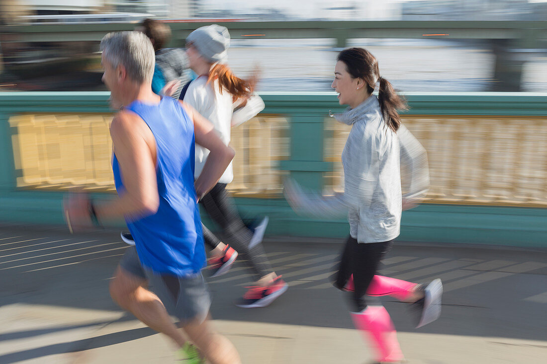 Runners running on bridge sidewalk