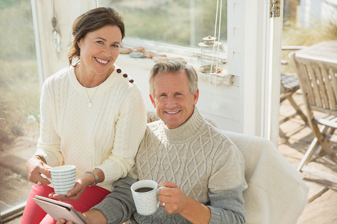 Mature couple using tablet and drinking coffee