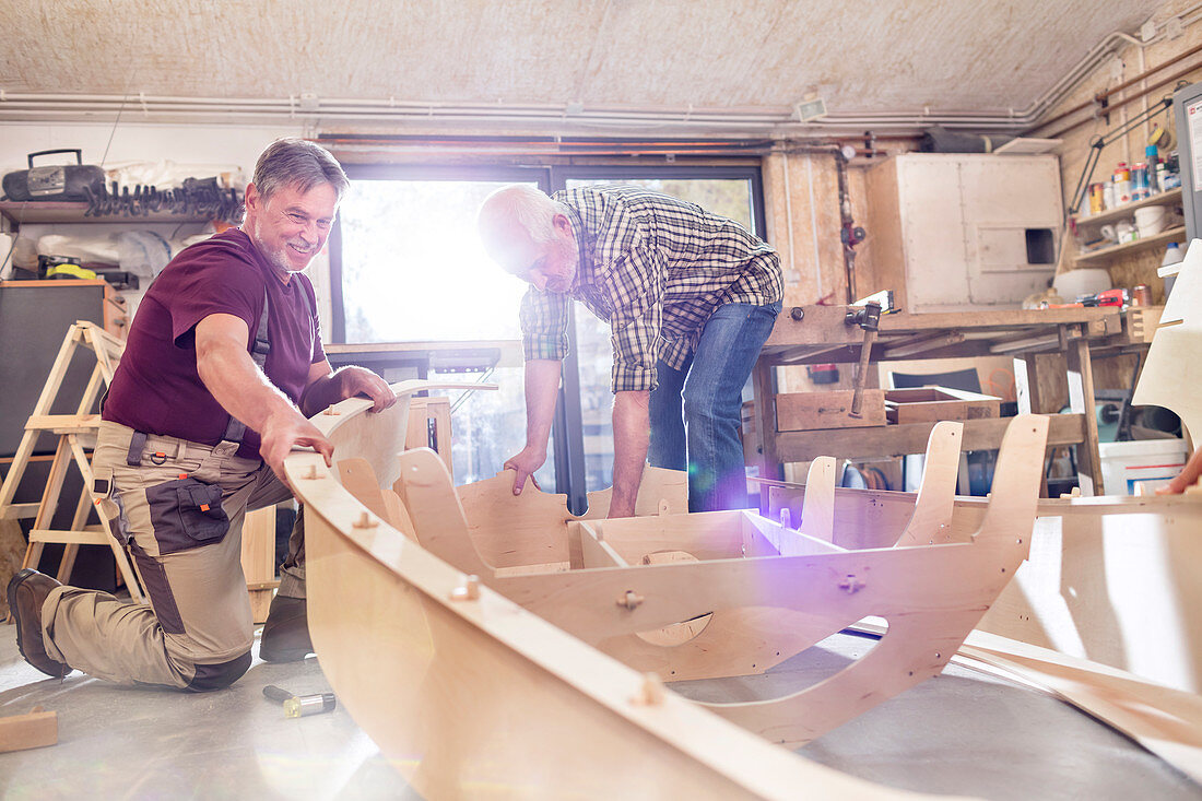 Male carpenters making wood boat