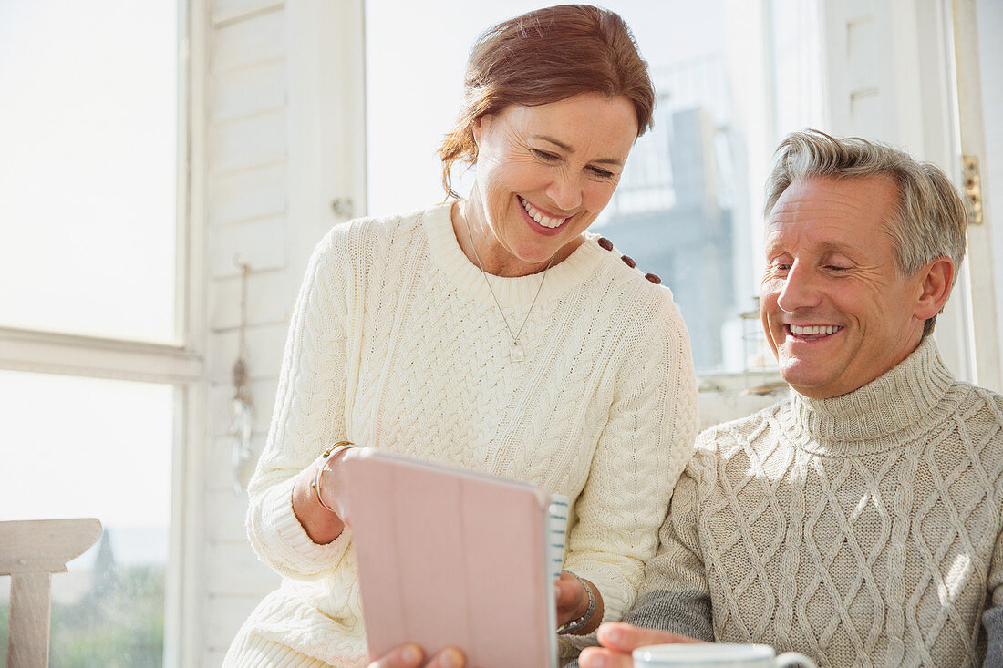 Smiling mature couple using tablet on sunny porch