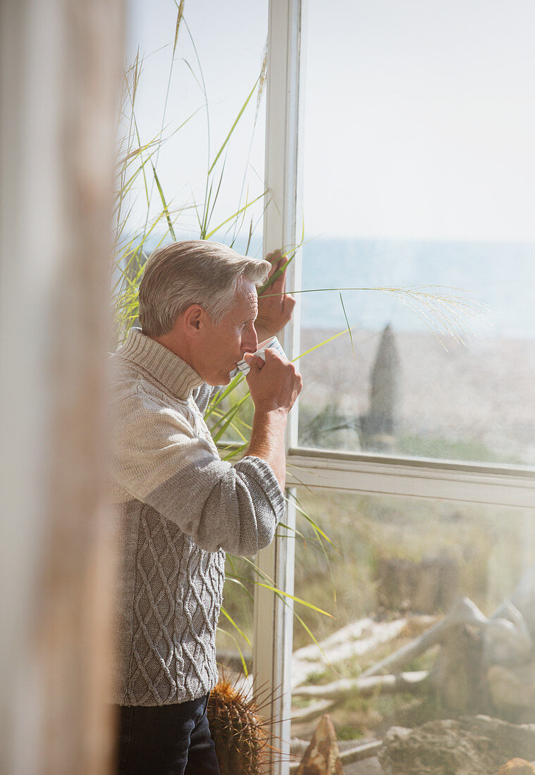 Senior man drinking coffee at window