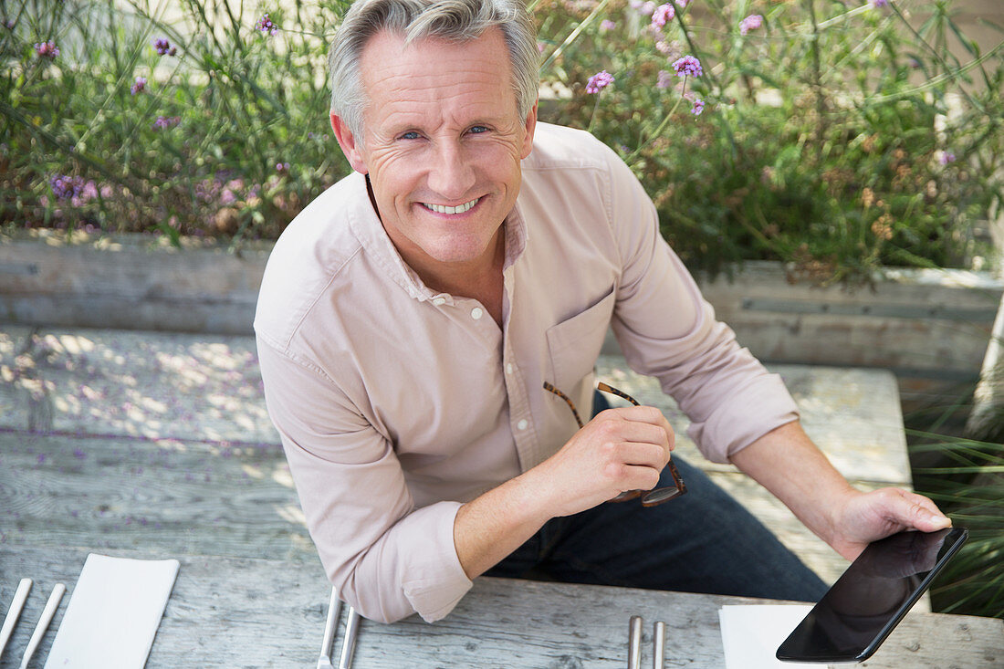 Portrait senior man using digital tablet on patio