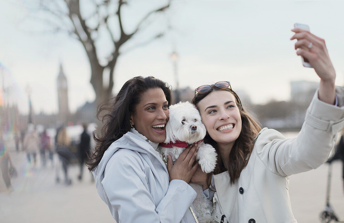 Lesbian couple with dog in urban park, London, UK