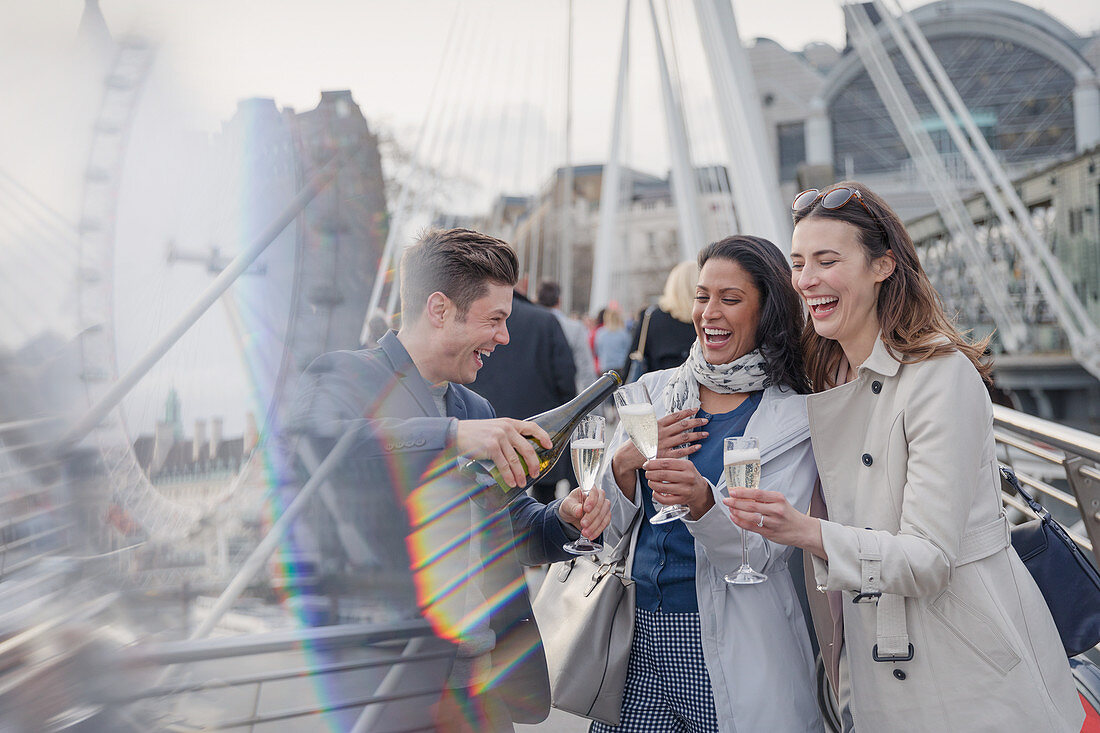 Friends celebrating, pouring champagne, London, UK