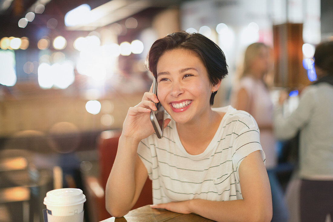 Smiling woman talking on cell phone in cafe