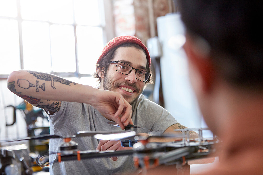 Smiling designer with tattoos assembling drone