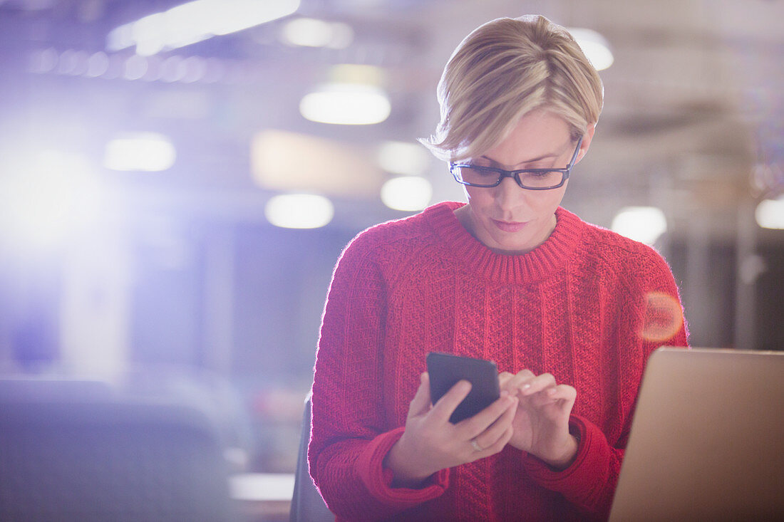 Businesswoman working late at laptop, texting
