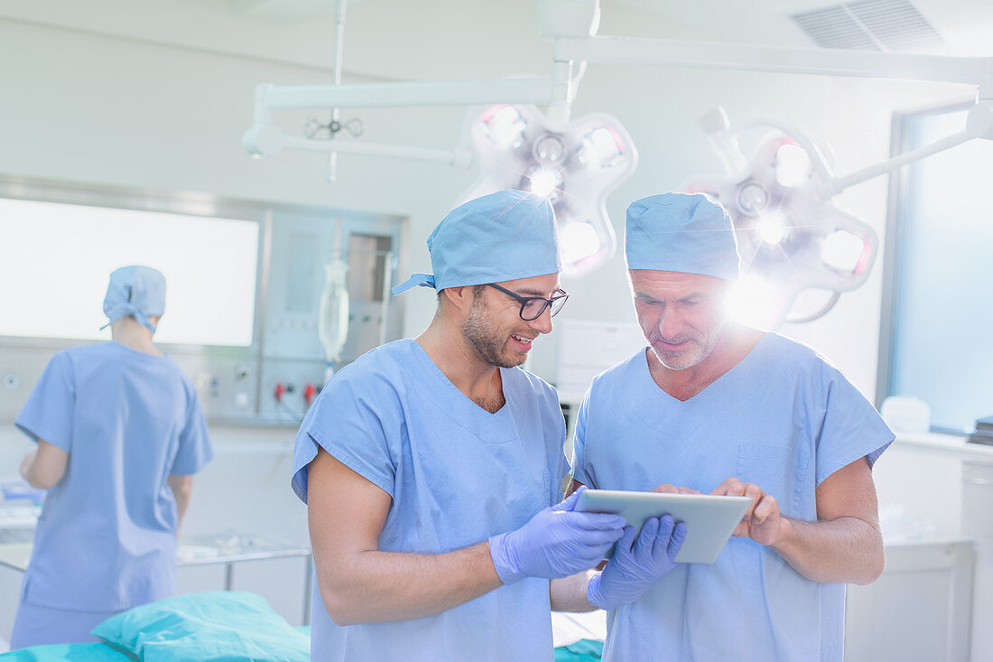 Male surgeons talking, using digital tablet