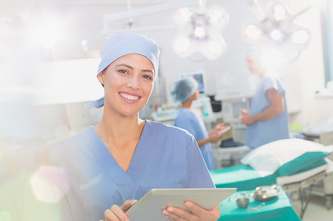 Portrait smiling female surgeon using tablet