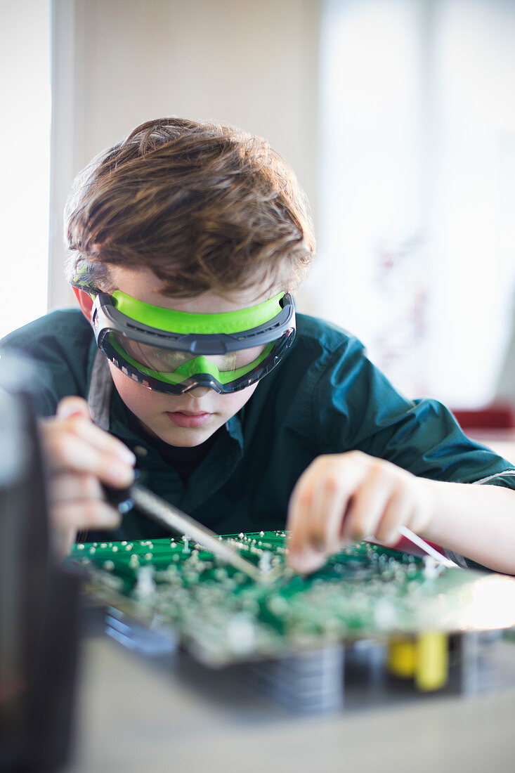 Student in goggles soldering circuit board