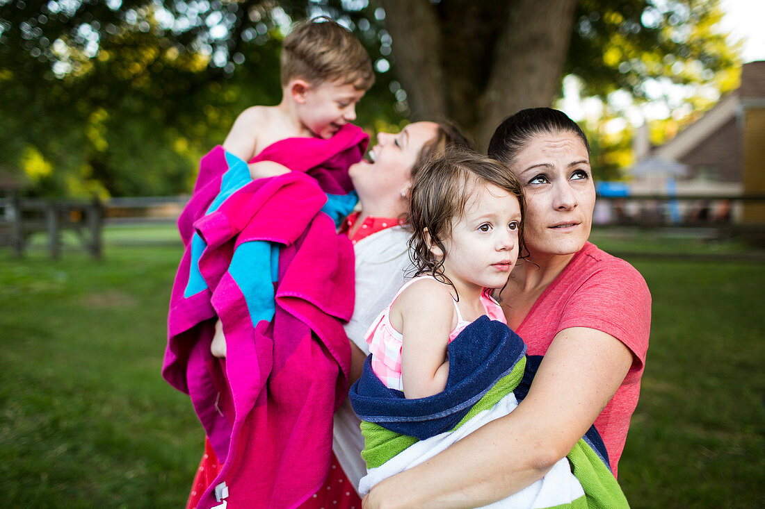 Lesbian mothers holding children wrapped in towel