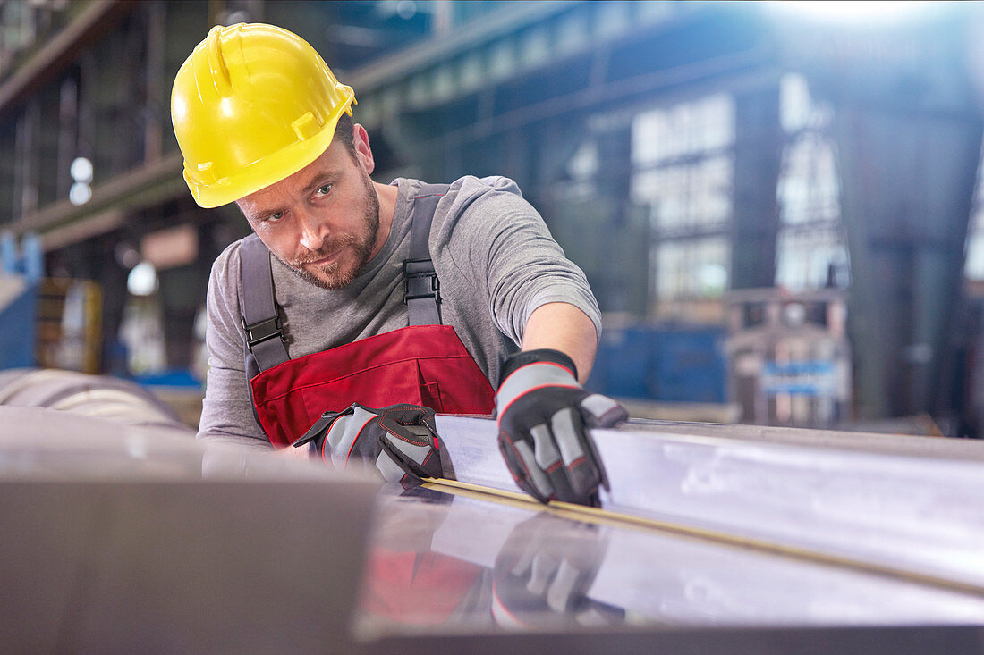 Focused male worker examining steel in factory