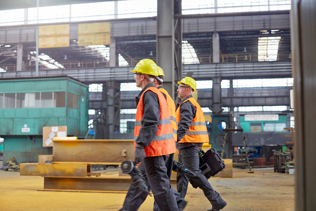 Male workers walking in steel factory