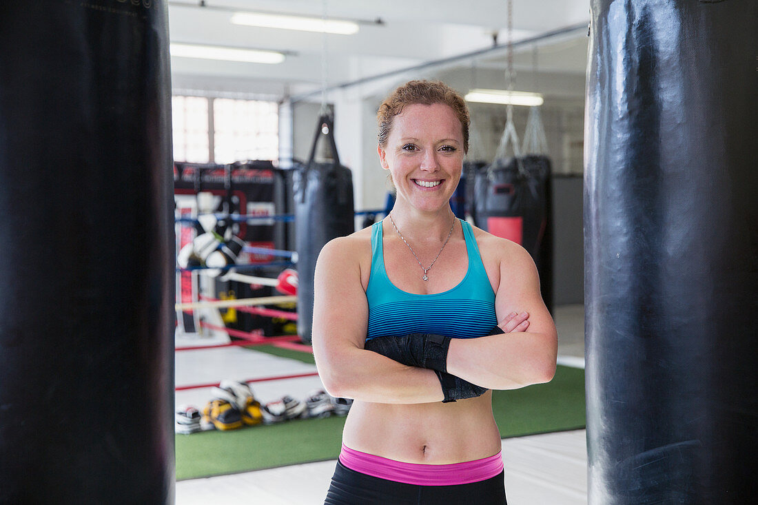 Portrait female boxer standing at punching bags