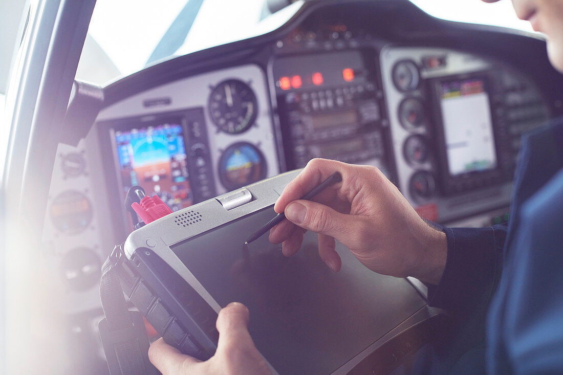 Airplane pilot using stylus on tablet in cockpit