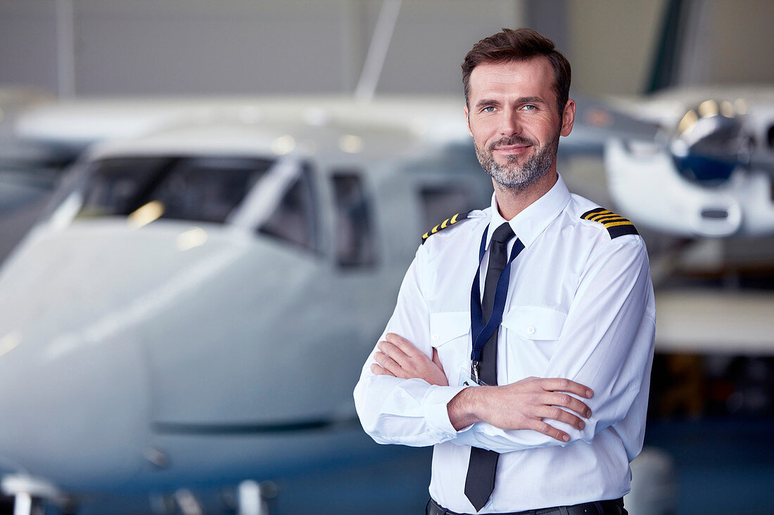 Portrait male pilot standing near airplane