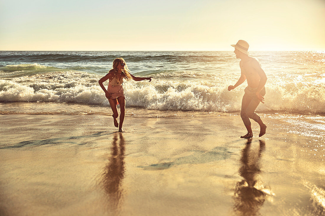 Playful young couple running in wet sand