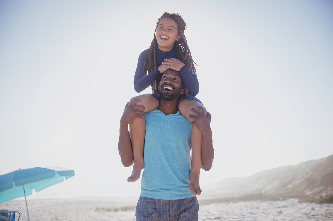 Playful father carrying daughter on shoulders