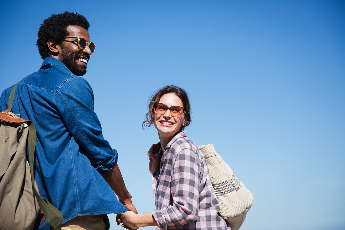 Portrait couple holding hands below blue sky