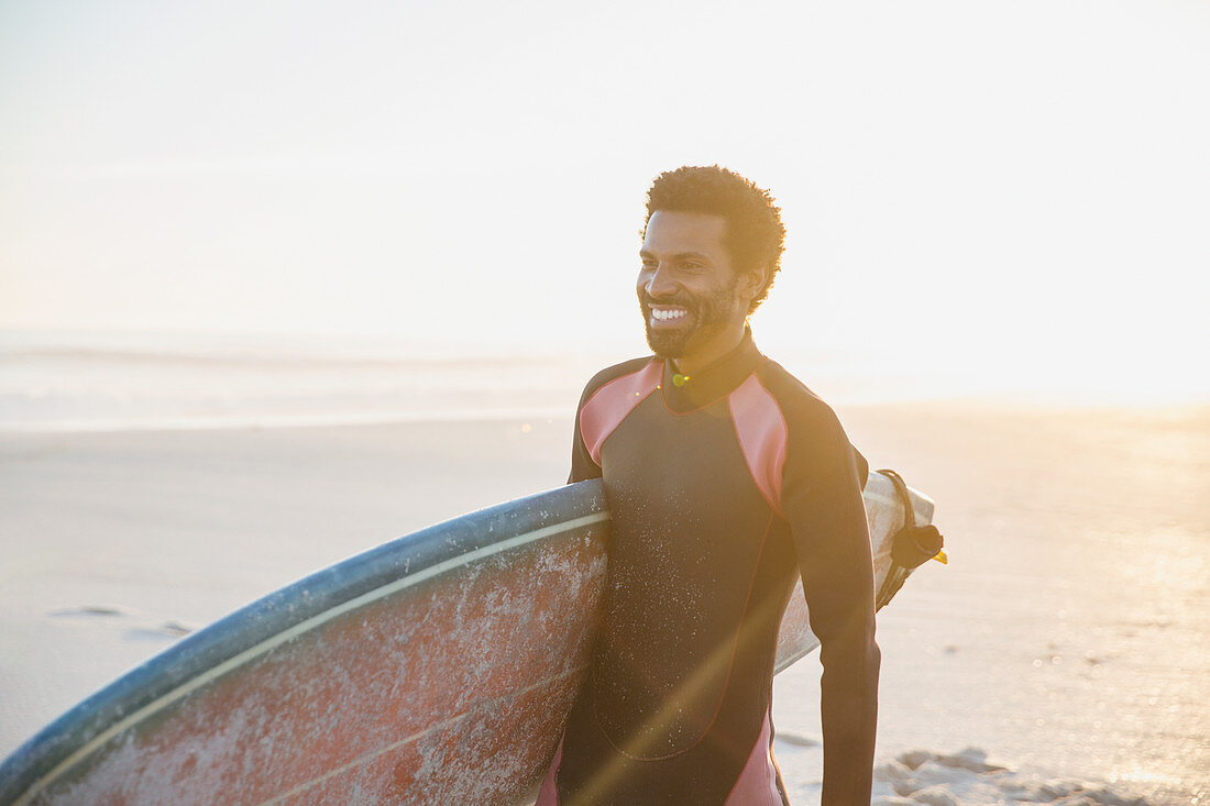 Smiling surfer walking with surfboard