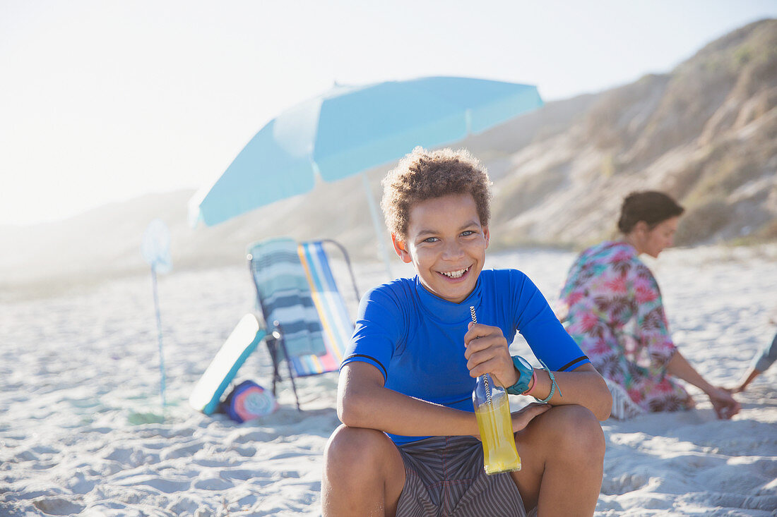 Portrait boy drinking juice on summer sunny beach
