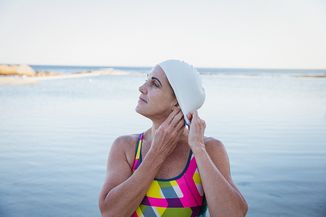 Female swimmer tucking hair into swimming cap
