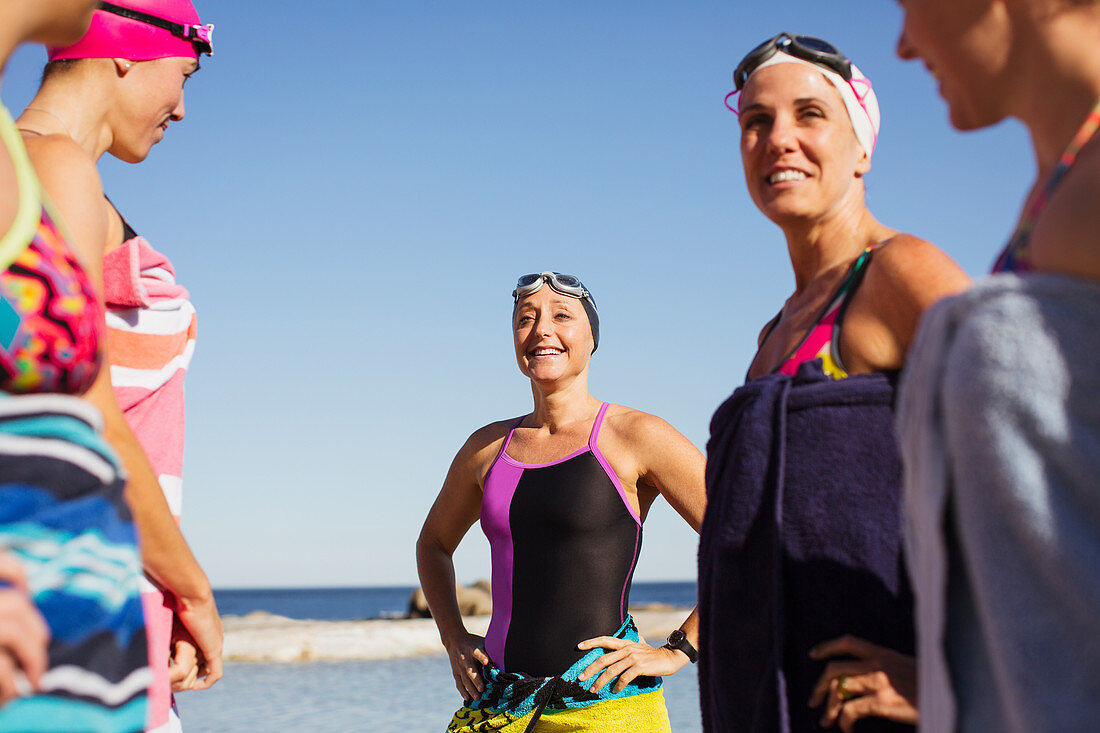 Smiling female swimmers wrapped in towels