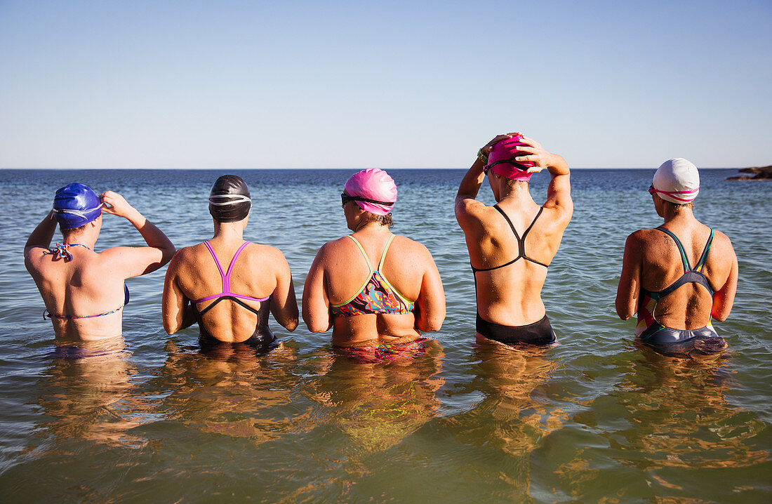 Female swimmers standing in a row surf