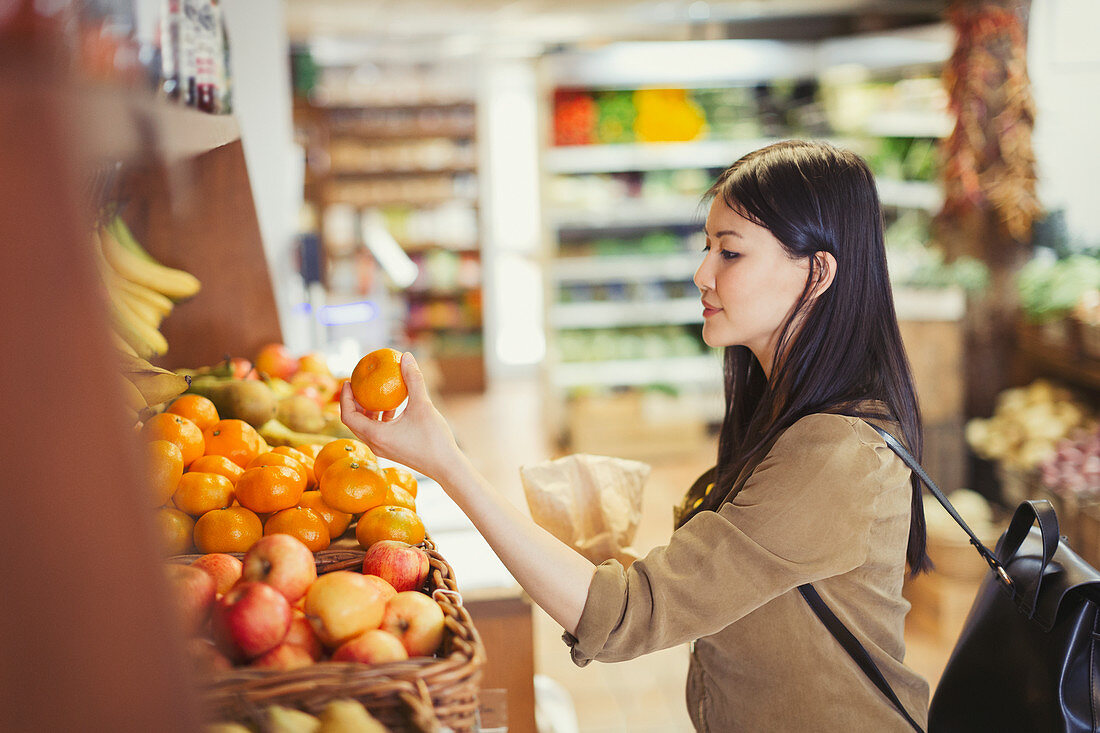 Young woman shopping, examining oranges