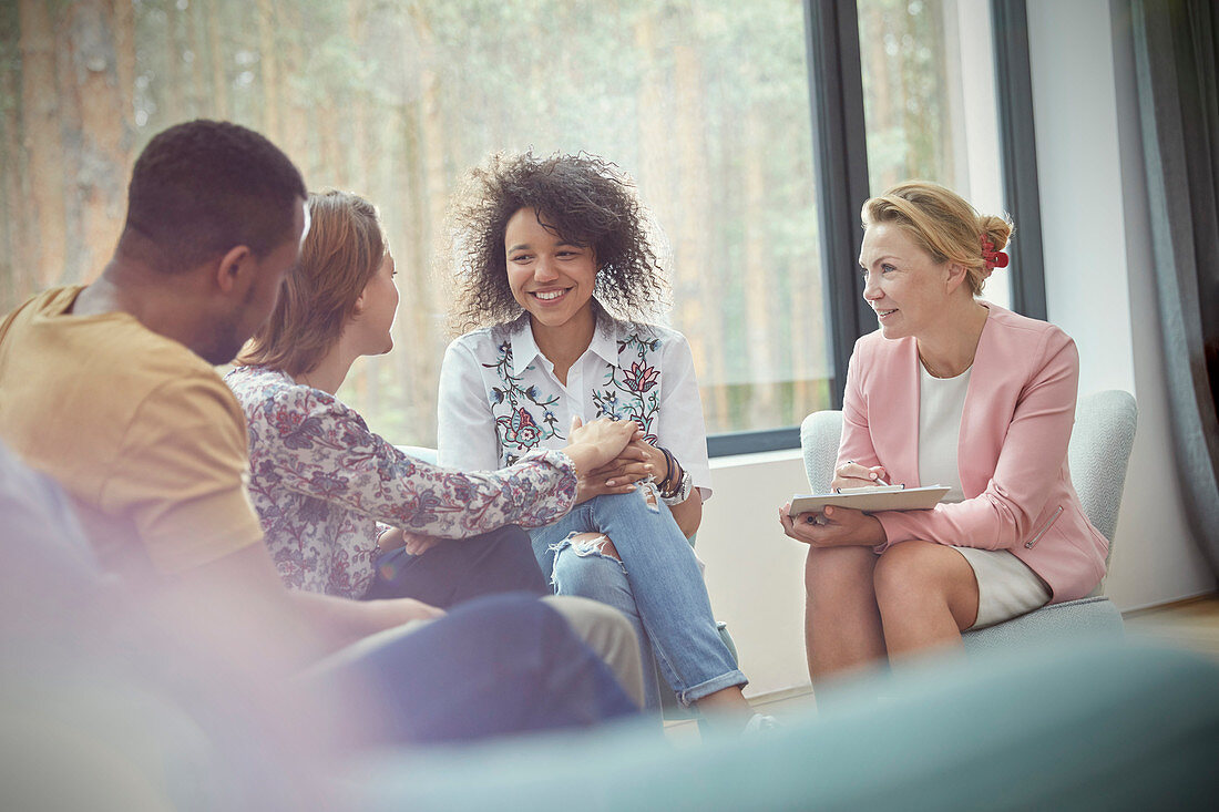 Smiling woman comforting woman in group therapy