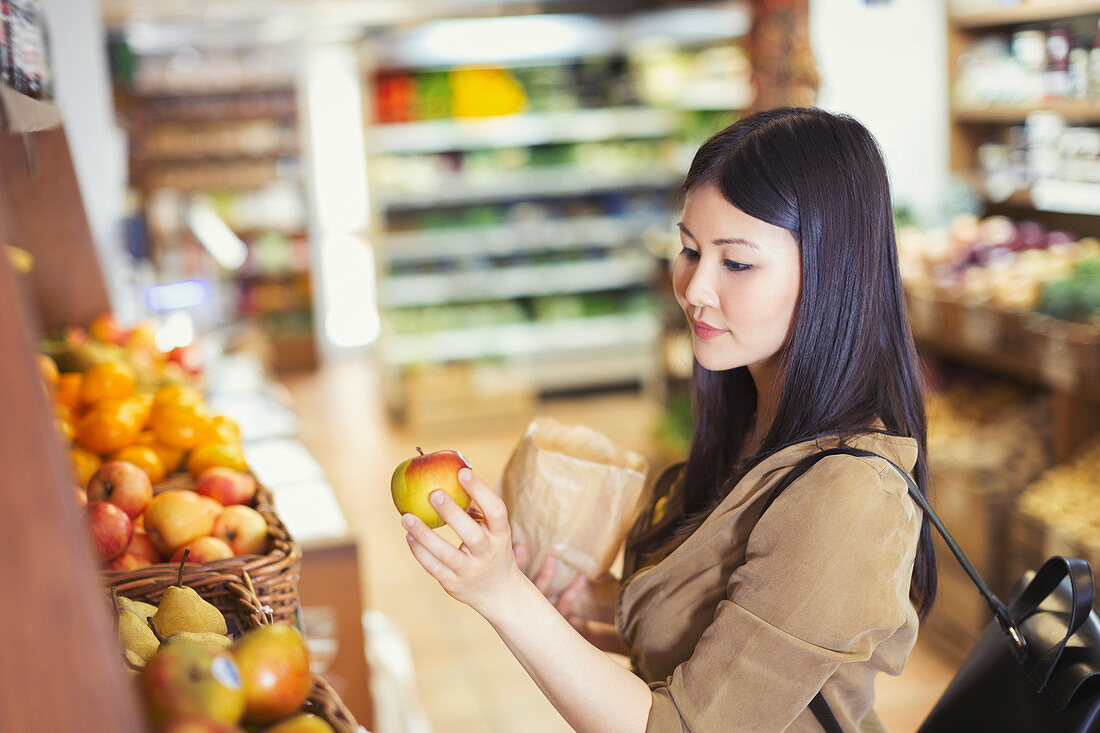 Young woman shopping, examining apple