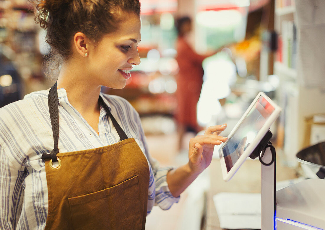 Female cashier using touch screen cash register