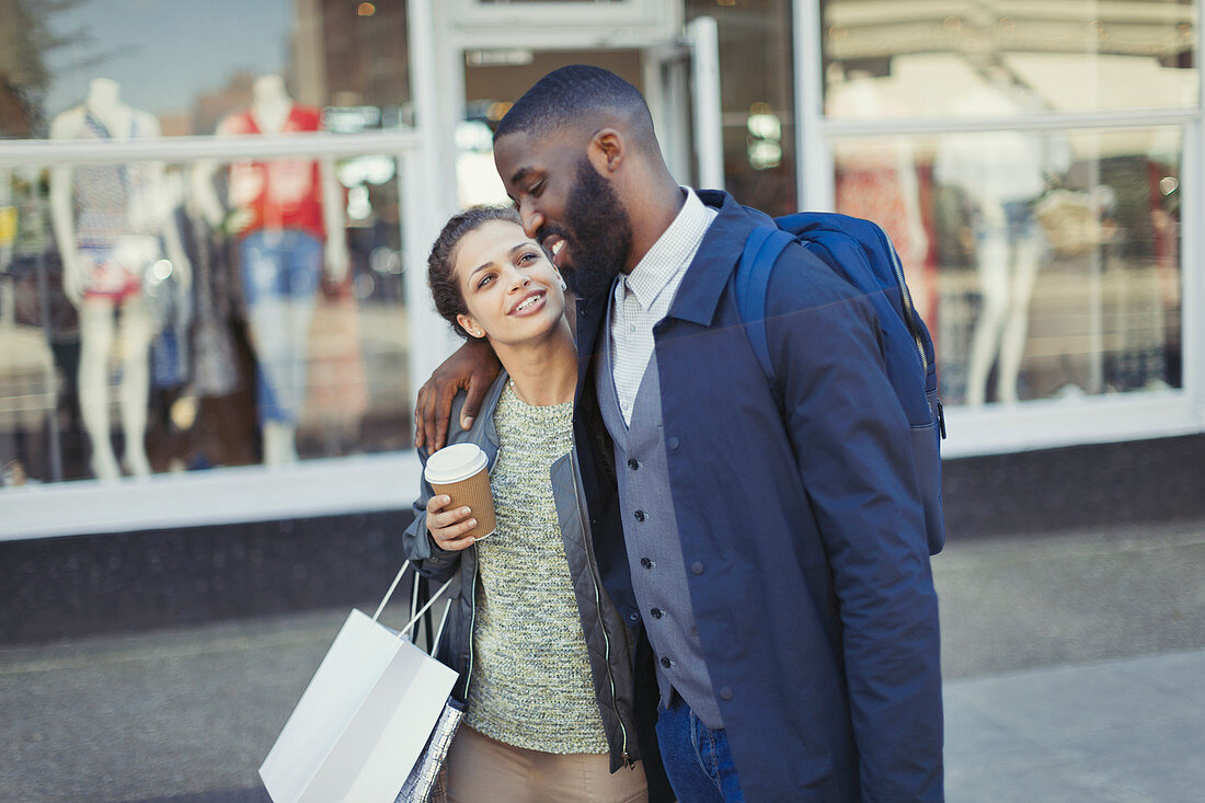 Affectionate couple with coffee and shopping bag
