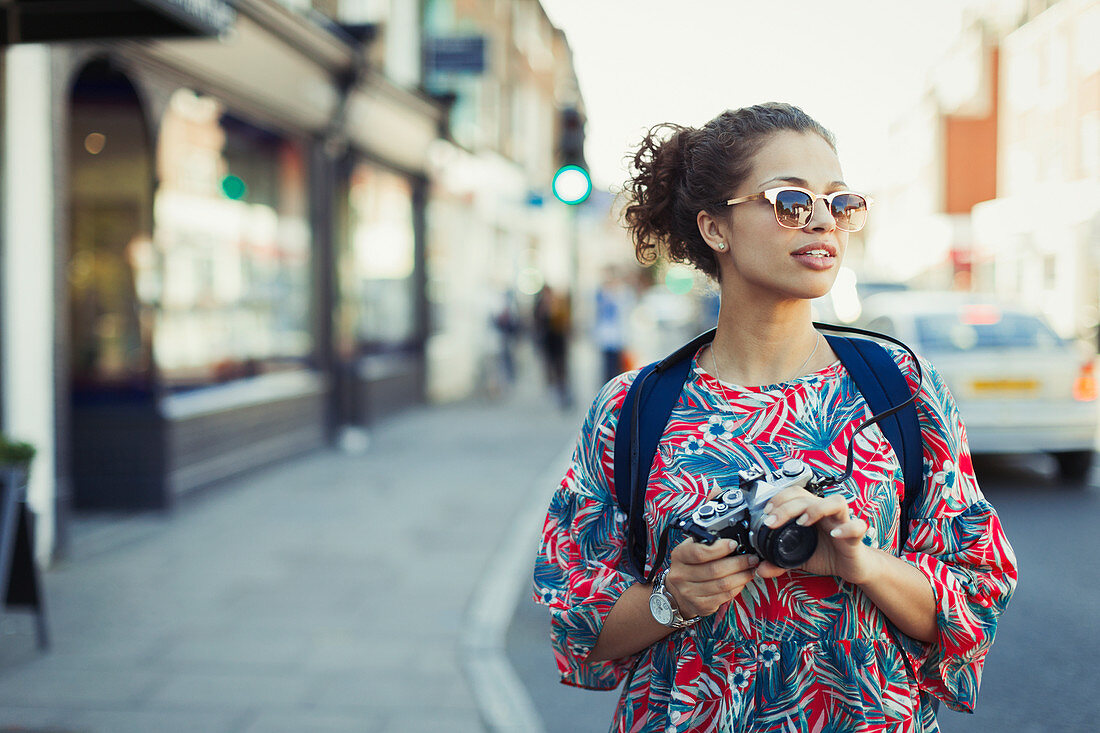 Young female tourist in sunglasses with camera