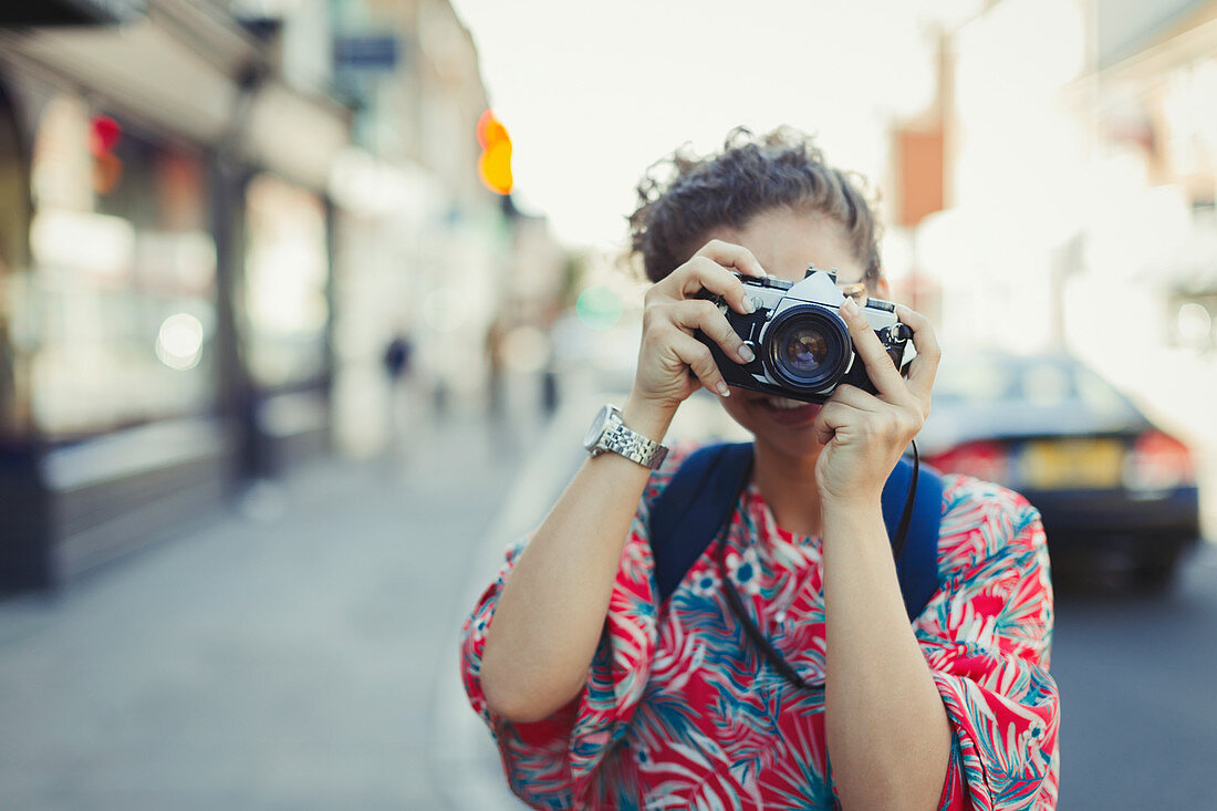 Portrait woman photographing with camera on street