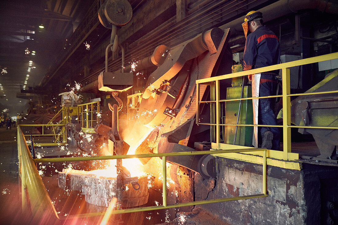 Steelworker on platform above molten furnace