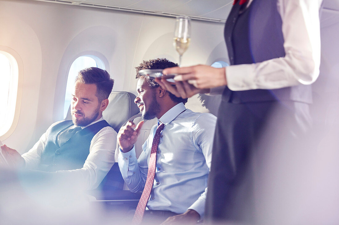 Flight attendant serving champagne to businessmen